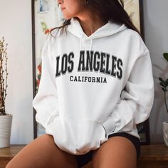 Wrap yourself in the laid-back and effortlessly cool vibes of Los Angeles with our Los Angeles Hoodie. This unisex hoodie is the perfect piece of apparel to show off your love for the city of angels. Made with high-quality materials, this hooded sweatshirt is comfortable and durable, making it ideal for everyday wear. Whether you're strolling along the palm-lined streets of LA or simply want to represent the city wherever you go, our Los Angeles Hoodie is a must-have. It also makes a great gift for anyone who appreciates California culture. Get yours today and let your LA spirit shine! 🖤 For oversized order 1-3 sizes up, refer to listing photos for sizes. RUNS ON THE SMALLER SIDE 🖤 Gildan 18500 🖤 Some Shrinkage may occur with washing 🖤 This unisex heavy blend hooded sweatshirt is relax Trendy College Hoodie, Trendy College Hoodie With Drawstring, Athleisure Hoodie With Letter Print For Leisure, Trendy White Sweats For Leisure, White Urban Hoodie For College, White Sporty Hoodie For Leisure, Oversized Comfortable Hoodie With Letter Print, Oversized Hoodie With Letter Print, Comfortable, White Hoodie For Leisure In Fall