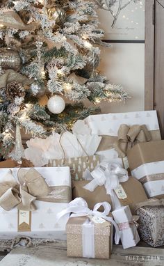 presents under the christmas tree are wrapped in brown and white paper with silver bows,