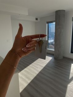 a hand holding a house key in front of a window