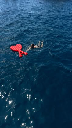 a man swimming in the ocean with a life jacket on his head and an orange buoy behind him