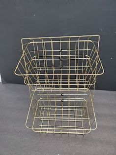 a metal wire basket sitting on top of a gray floor next to a white wall