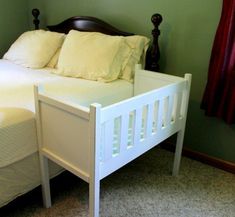 a small white bed sitting in a bedroom next to a green wall and red curtains