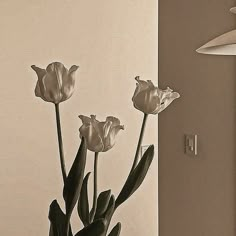 a vase with flowers in it sitting on a table next to a wall mounted light