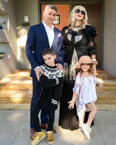 a man, woman and two children standing in front of a house with their arms around each other