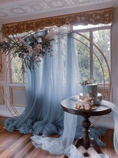 a table with a cake on top of it in front of a curtained window