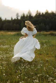 a woman in a white dress is running through the grass