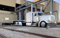 a large semi truck parked in front of a building next to train tracks and freight containers