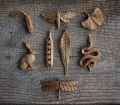 carved wooden animals are arranged on a wood table with leaves and other things around them