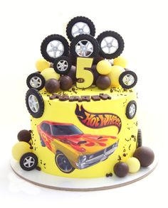 a yellow birthday cake decorated with wheels and tires