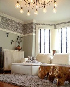 a living room filled with furniture and a chandelier hanging from the ceiling above it