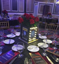 the table is set with plates, silverware and red roses