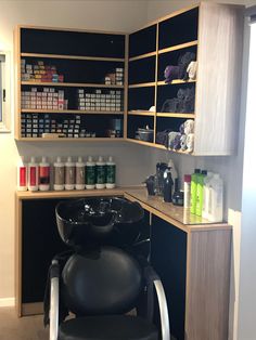 a hair salon with black chairs and shelves filled with bottles on the wall next to it