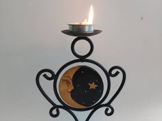 a metal candle holder with a lit candle in it's center and an image of a woman on the front