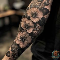 a man's arm with flowers and leaves tattooed on the arm, in black and white