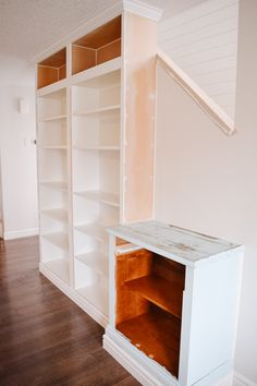 an empty room with white shelves and wooden flooring in the middle, painted off