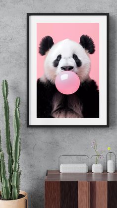 a panda bear with a bubble gum in its mouth hanging on a wall next to a cactus