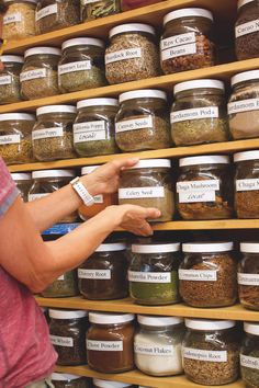 a woman is pointing at some spices on shelves