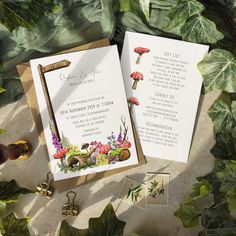 wedding stationery with flowers and mushrooms on it, surrounded by greenery in the background