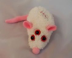 a white stuffed animal with red eyes laying down