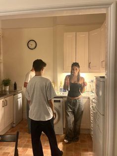 two people standing in a kitchen next to an open refrigerator