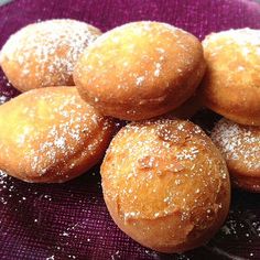 a purple plate topped with donuts covered in powdered sugar