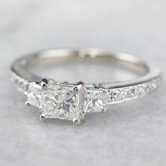 three stone diamond engagement ring in white gold with side stones on the band and pave set shoulders