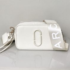 Authentic Marc Jacob’s Snapshot Bag In Cream + Champagne. Champagne Strap With Gold Detailing. Strap Included And Bag! Saffiano Leather Dual Top Zip Closure Removable And Adjustable Webbing Strap Interior Slip Pocket, Exterior Slip Pocket Faille Lining 7in L X 2in D X 4in H 18cm L X 6cm D X 11cm H Strap 8-57in L X 2in D (21-144 Cm L X 5cm D) Strap Drop 27in (68cm) Modern White Shoulder Bag With Logo Strap, White Bag With Logo Strap For Everyday Use, White Bags With Logo Strap For Everyday Use, Luxury White Box Bag With Adjustable Strap, Designer Bags With Logo Strap, White Shoulder Bag With Logo Strap For Everyday, Luxury White Shoulder Bag With Logo Strap, Designer Bags With Logo Strap For Everyday, Luxury Bags With Logo Strap And Top Handle