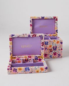 three small boxes with flowers on them sitting next to each other in front of a white background