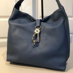 Dooney & Bourke Belvedere Logo Lock Shoulder Bag In Dusty Blue. Bag Features Include: Pebble Leather Interior Zip Pocket Interior Cell Phone Pocket Three Interior Slip Pockets Interior Key Hook Lined In Dooney & Bourke's Red Cotton Bottom Feet Approximate Size - 12.5" L X 13" H X 6" W Weight - 2 Lbs. 3 Oz. New With Tags; Unwrapped Only For Photos. Luxury Blue Hobo Bag For Travel, Formal Blue Shoulder Bag With Metal Hardware, Luxury Blue Hobo Bag For Everyday Use, Blue Shoulder Bag With Metal Hardware And Double Handle, Blue Bags With Silver-tone Hardware For Daily Use, Everyday Blue Shoulder Bag With Metal Hardware, Everyday Blue Bag With Silver-tone Hardware, Blue Bags With Metal Hardware For Everyday Use, Blue Double Handle Bag With Metal Hardware