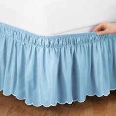 a bed with a blue ruffled bedskirt on it's bottom edge