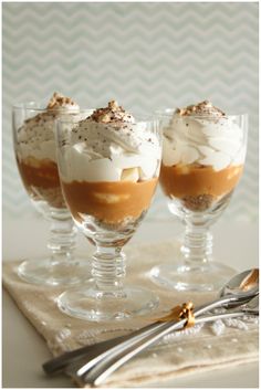 three glasses filled with dessert sitting on top of a table