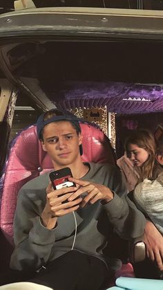 two people sitting in the back of a car looking at their cell phones