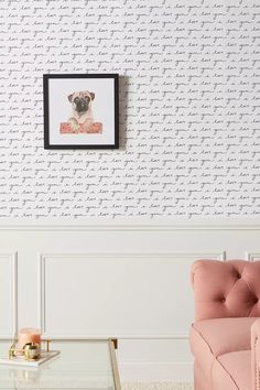 a pink chair in front of a wall with a pug on it's back