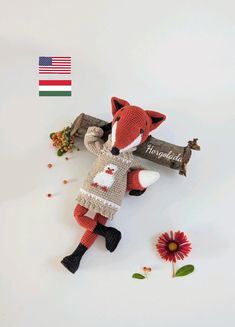 a stuffed animal laying on top of a white surface next to flowers and a flag