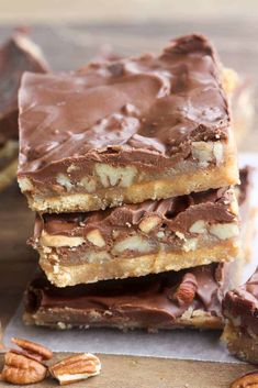 three pieces of chocolate pecan bar stacked on top of each other with pecans