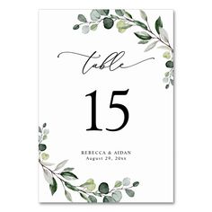 the wedding table numbers are printed on white paper with greenery and leaves in black ink