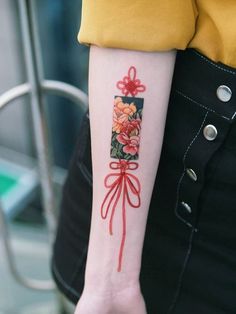 a woman with a tattoo on her arm has a red bow and flowers in it