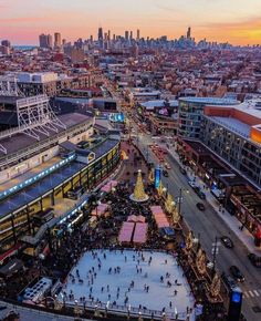 an aerial view of people skating on the ice rink in front of a cityscape