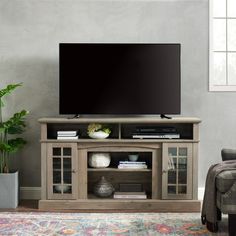 a flat screen tv sitting on top of a wooden entertainment center next to a chair