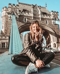 a woman sitting on top of a car in front of a bridge