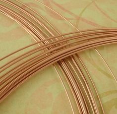 several pieces of copper colored wire on a green and pink background with swirly designs