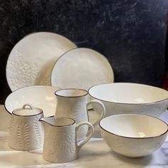 a table topped with white dishes and plates on top of a marble slabd counter