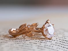 two gold rings sitting on top of an open book with a diamond in the middle