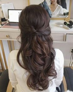 a woman sitting in front of a mirror with her hair pulled back into a half - updo