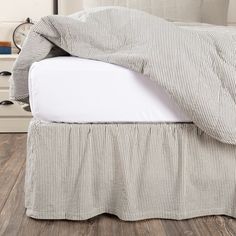 an unmade bed with white sheets and black and white striped bedspread on it