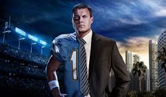 a man wearing a suit and tie standing in front of a stadium with palm trees