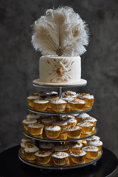 three tiered cake with white frosting and gold cupcakes