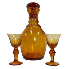 an orange glass decanter and two wine glasses on a white background with clippings