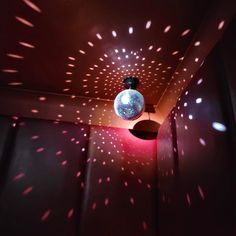 a disco ball hanging from the ceiling in a dark room with pink and white lights