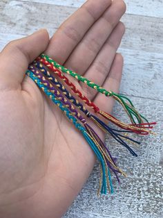 a hand is holding several different colored bracelets